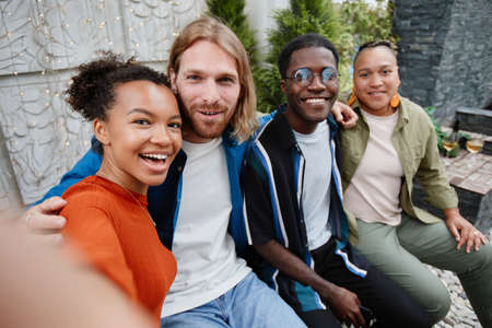 POV diverse group of young people looking at camera via video chat while having fun during outdoor...
