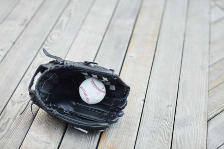 Close-up of black baseball mitt with ball placed on wooden surfaceの写真素材