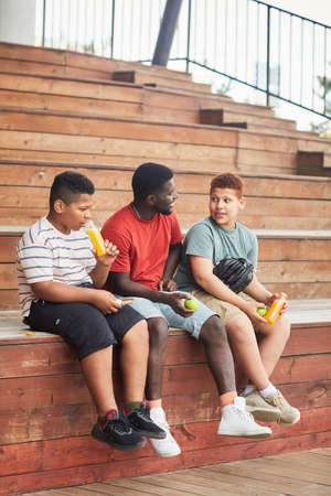 African American family of fans consisting of father and sons sitting in stands and talking togetherの写真素材
