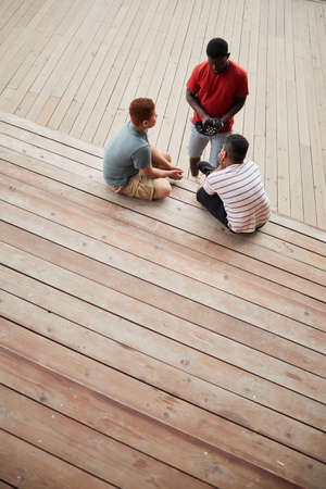 Above view of African-American man putting baseball glove on hand while preparing for baseball training with boysの写真素材