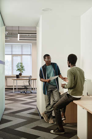 Black young office workers making copies of reports and contracts and discussing big project they...