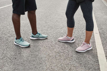 Close-up of young couple in sports shoes meeting outdoors to train together