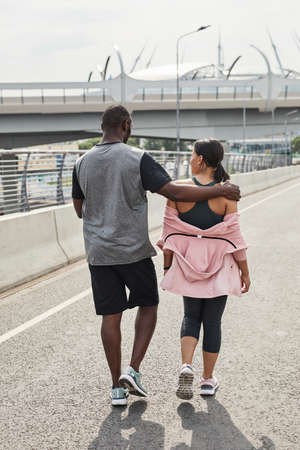 Rear view of young couple talking to each other during their walk in the cityの写真素材