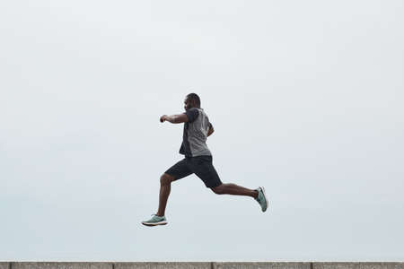 African young man exercising outdoors, he jumping over a barrierの写真素材