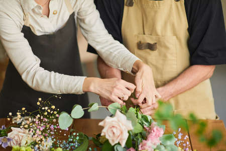 Close up of two florists arraigning flower compositions in cozy workshop, copy spaceの写真素材