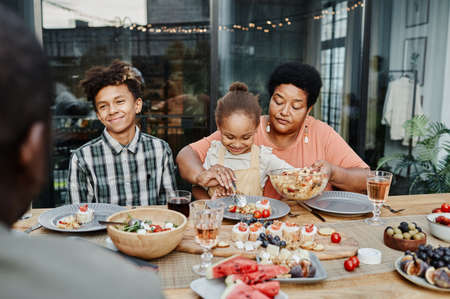 Portrait of happy senior woman with grandchildren enjoying family dinner togetherの写真素材