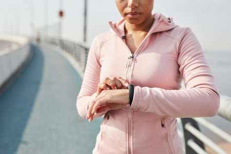 Young woman checking her pulse on fitness bracelet after running outdoorsの写真素材