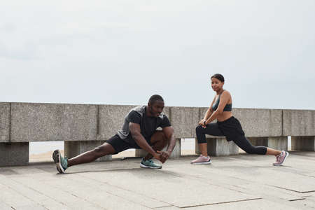 African young couple doing exercises together during sports training outdoors