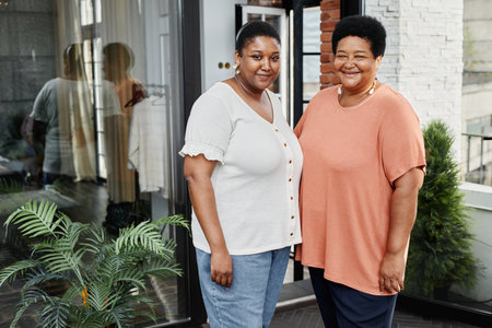 Portrait of adult African-American woman posing with mother at terrace outdoors and looking at camera, multi-generation conceptの写真素材