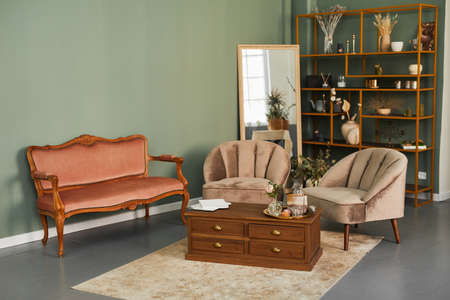 Background image of elegant salon interior with comfy velvet sofa and antique furniture in green tonesの写真素材
