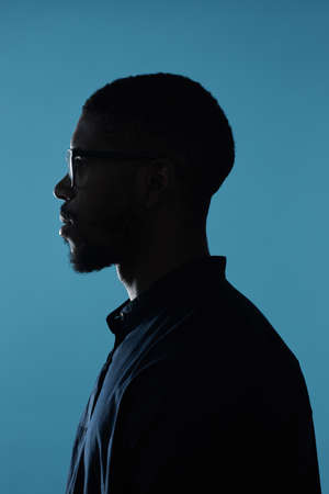 Side view profile outline of African-American male silhouette against deep blue backgroundの写真素材