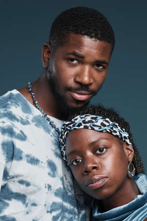 Vertical portrait of young African-American couple wearing casual street style clothes while posing...
