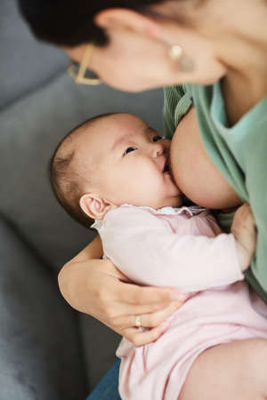 Close-up of cute baby girl eating on her mothers hands before sleepingの写真素材