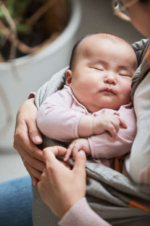 Close-up of cute little child sleeping in her mothers handsの写真素材