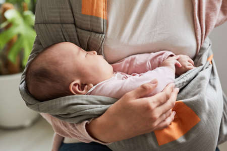 Close-up of cute baby girl sleeping while her mother holding her on handsの写真素材