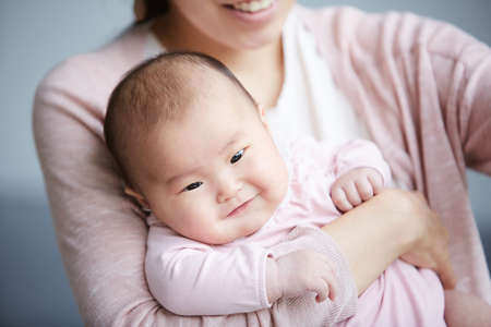 Close-up of Asian little child smiling while her mother holding herの写真素材