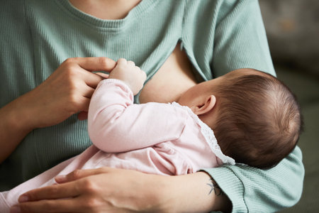 Close-up of mother feed her month son with breast milk at homeの写真素材