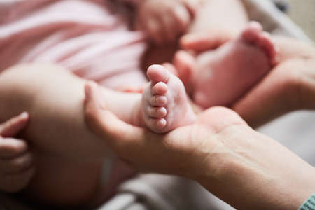 Close-up of mother holding little feet of her newborn child in her handsの写真素材