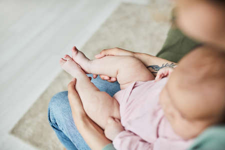 High angle view of young mother sitting in the room with her baby on her kneesの写真素材