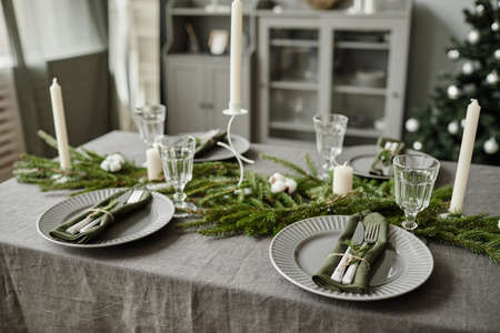 High angle background image of dining room table decorated for Christmas with fir tree branches and candles, copy spaceの写真素材