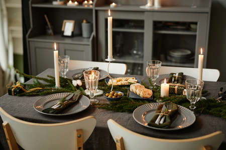Background image of cozy table setting decorated for Christmas with candles lit in grey tones, copy spaceの写真素材