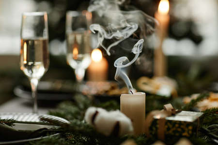 Close up of elegant white candle on Christmas dining table with smoke waving , copy spaceの写真素材