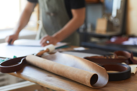 Close up of genuine leather on wooden table in tanners workshop, copy space