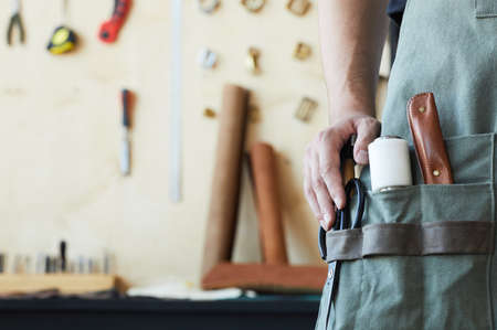 Close up of various leathermaking tools in apron pocket of male tanner, copy spaceの写真素材