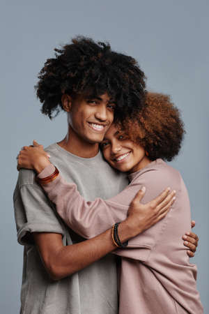 Minimal vertical portrait of young African-American couple with natural curly hair smiling at camera...