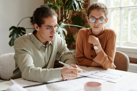 Portrait of two young architects discussing floor plan project at team meetingの写真素材
