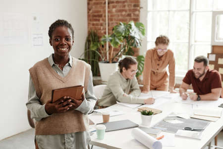 Portrait pof young black woman smiling at camera while working in creative design studio, copy spaceの写真素材