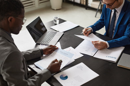High angle view at two businessmen reading documents during meeting in office, copy space