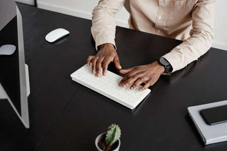 High angle of black businessman using computer at desk in minimal office interior, copy spaceの写真素材