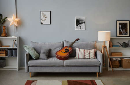 Background image of teenage boys room with acoustic guitar on cozy blue sofa, copy spaceの写真素材