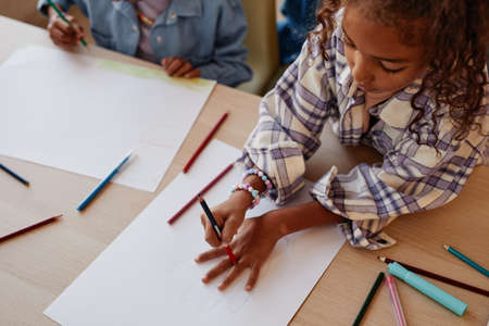High angle portrait of cute African-American girl drawing with family at home, copy spaceの写真素材