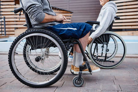 Close-up of people with disability sitting in wheelchairs and talking to each other they spending...