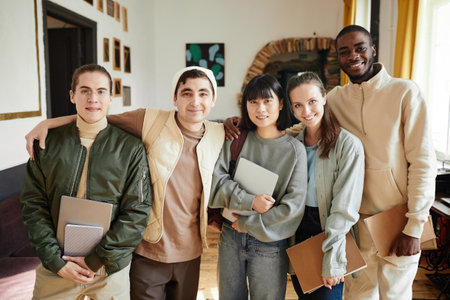 Portrait of group of students with books smiling at camera standing in the classroom of universityの写真素材