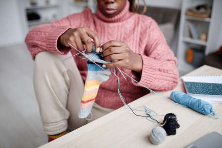 Cropped portrait of young African-American woman knitting at home in cozy room, copy spaceの写真素材