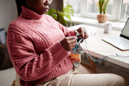Cropped portrait of young African-American woman knitting at home and enjoying cozy weekend, copy spaceの写真素材