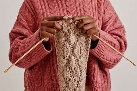 Close up of young African-American woman knitting scarf and wearing cozy sweater, copy spaceの写真素材