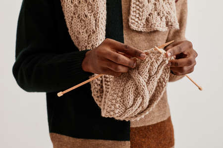 Minimal close up of unrecognizable African-American man knitting scarf, copy spaceの写真素材