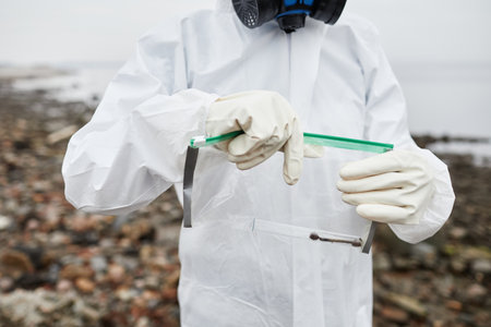 Cropped shot of man in hazmat suit collecting probes outdoors, industrial pollution concept, copy spaceの写真素材