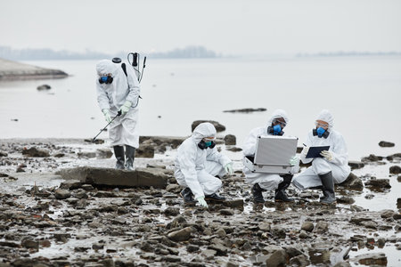 Group of workers wearing hazmat suits collecting samples by water, toxic waste and pollution concept, copy spaceの写真素材