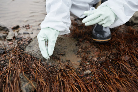 Close up of unrecognizable scientist wearing hazmat suit collecting soil probes, focus on gloved hands, copy spaceの写真素材