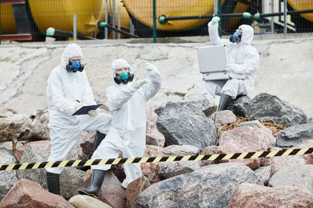 Group of people in hazmat suits working at ecological disaster site, toxic waste and pollution concept, copy spaceの写真素材