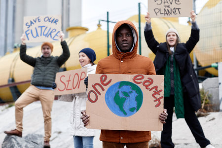 Front view at diverse group of people holding signs holding and shouting while protesting at environmental disaster siteの写真素材