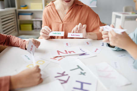 Close-up of teacher showing cards with new words to children at the table during English lesson at schoolの写真素材