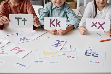 Close-up of group of children playing with cards at the table, they learning to read in Englishの写真素材
