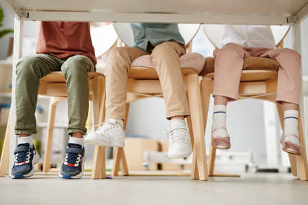 Group of school children sitting on chairs at desk during a lesson in the classroomの写真素材
