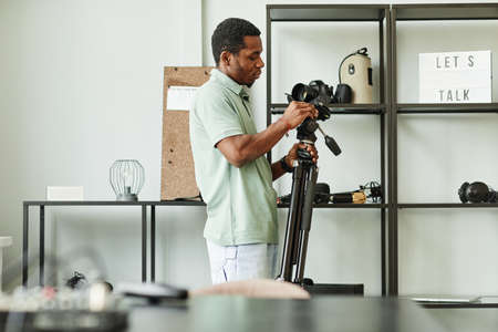 Side view portrait of African-American man setting up recording equipment in studio, copy spaceの写真素材